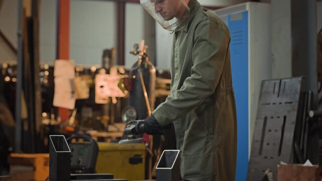 Young adult Caucasian man wearing protective face shield grinding metal tube with angle grinder. Clip is perfect for industrial manufacturing and vocational training videos