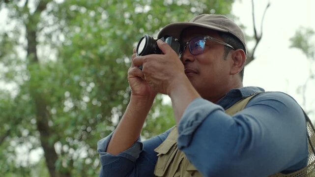 Experienced senior male photographer capturing the beauty of nature in a forest. Active aging creative retirement, outdoor photography, lifelong passion, healthy longevity and fulfilling lifestyle.
