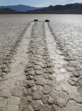 View of the Racetrack Playa in Death Valley with its iconic sliding rocks and long trails etched into the cracked, dry lake bed, Death Valley, California, United States.