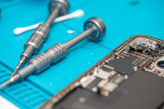 Technician repairing smartphone components on a workbench in electronics repair laboratory