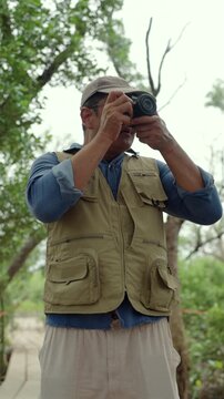 Experienced senior male photographer capturing the beauty of nature in a forest. Active aging creative retirement, outdoor photography, lifelong passion, healthy longevity and fulfilling lifestyle.

