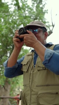 Experienced senior male photographer capturing the beauty of nature in a forest. Active aging creative retirement, outdoor photography, lifelong passion, healthy longevity and fulfilling lifestyle.
