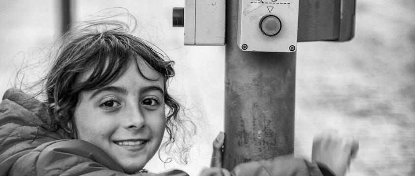 Young girl pressing pedestrian sign at a traffic light.
