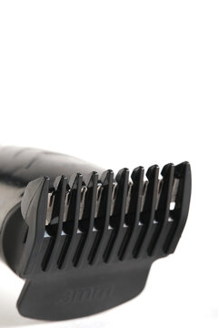 Vertical close up shot electric hair trimmer head with plastic guide comb and cutting blades.