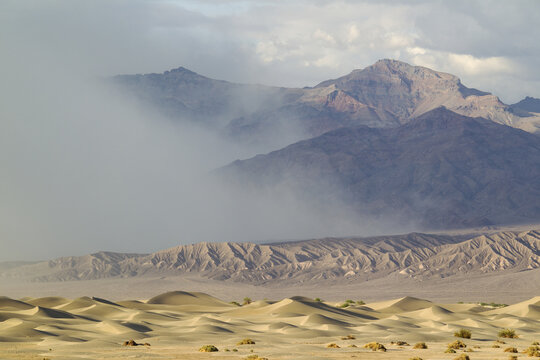 View of Mesquite Flat Sand Dunes with wind-blown sand and dramatic mountains in the background in Death Valley, California, United States.