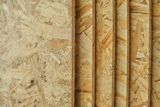 Close up perspective multiple stacked OSB wood boards showing textured edges and surface grain.