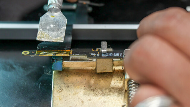 Professional electronics repair specialist removing damaged port with solder wick closeup