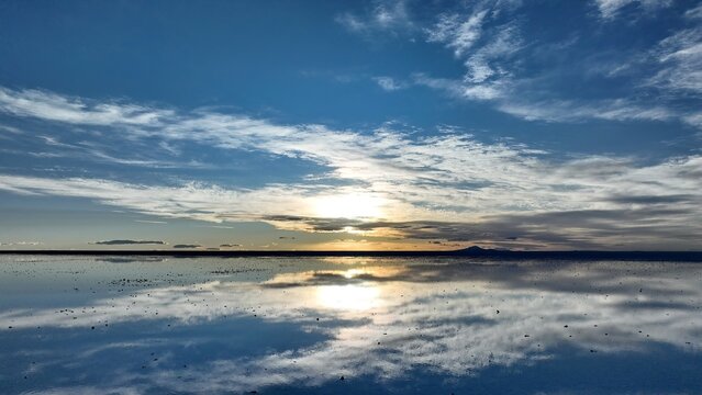 Aerial view of the vast Uyuni Salt Flat at sunset with dramatic cloud reflections on the water surface in Uyuni, Potosi Department, Bolivia.