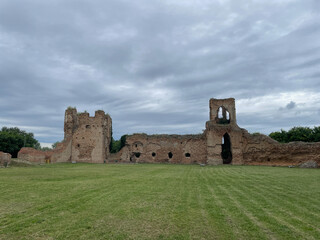 Ruins of a stone castle in an open landscape with a weathered wall, grassy foreground, and cloudy sky, conveying history, solitude, and timeless ruin ambiance © Alexander