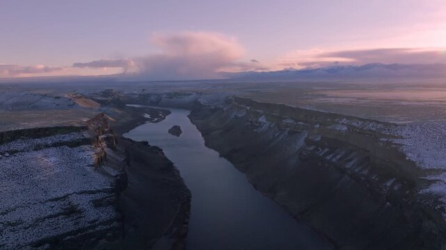 Aerial view of the Snake River winding through the snowy canyon of the Morley Nelson Snake River Birds of Prey National Conservation Area at sunset in Murphy, Idaho, United States.
