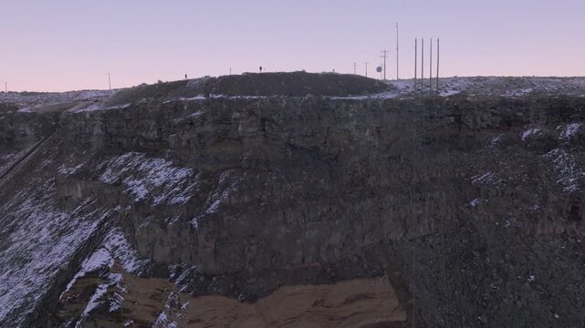 Aerial view of rocky cliffs of the Morley Nelson Snake River Birds of Prey National Conservation Area with patches of snow and communication towers on the ridge in Murphy, Idaho, United States.