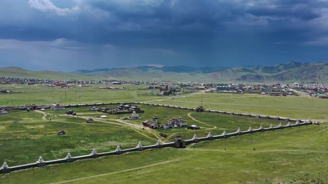 Aerial view of Erdene Zuu Monastery with its historic walled enclosure and stupas set against a dramatic stormy sky in the vast green landscape of Kharkhorin, Ovorkhangai, Mongolia.