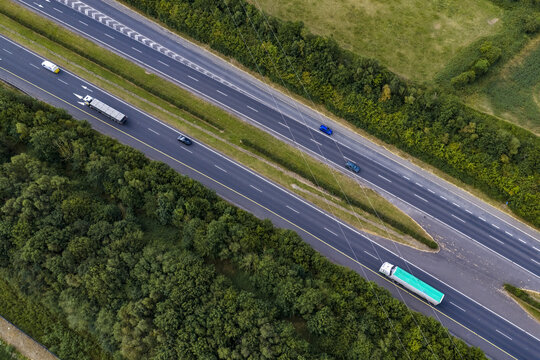 Aerial view of a multi-lane highway with cars and trucks driving through a lush green landscape in Drogheda, County Louth, Ireland.