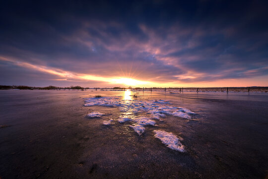 Golden Sunburst Over Frozen Winter Field with Dramatic Clouds