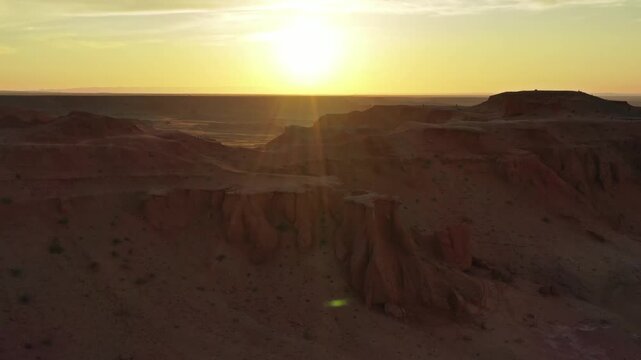 Aerial view of Flaming Cliffs at sunset with red sandstone formations and golden light in Bulgan, Omnogovi, Mongolia.