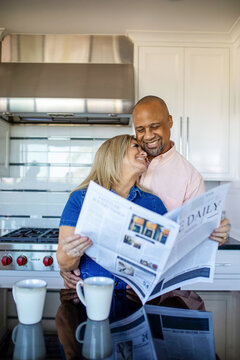 Happy couple reading newspaper together.