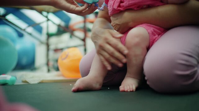 Adult hands providing pacifier to infant in pink romper, symbolizing care, comfort, and maternal love during playtime