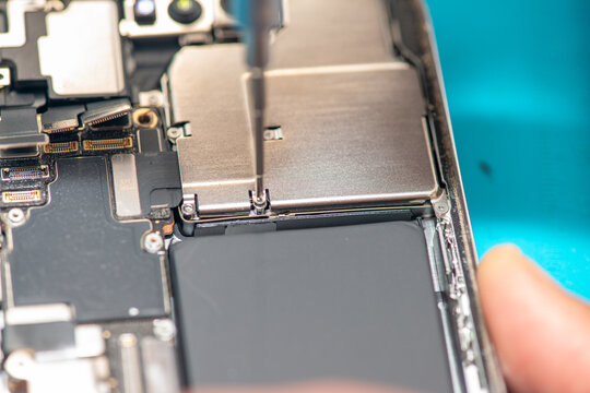 Technician repairing smartphone components in laboratory using precision tools and equipment