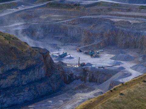 Aerial view of a large stone quarry with heavy machinery, piles of gravel, and excavated rock faces in Drogheda, County Louth, Ireland.