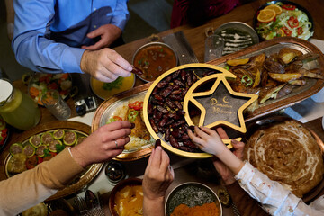 Fototapeta premium Ramadan Iftar Family Sharing Dates and Festive Food Gathering Around a Traditional Table