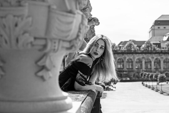 Beautiful woman in dark red velvet corset and black lace veil posing against historic Zwinger palace architecture in Dresden, gothic style and baroque aesthetics concept 