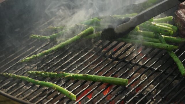 Fresh green asparagus spears char over charcoal barbecue grill