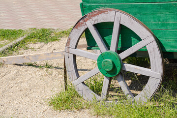 Close up of antique wooden cart wheel with green hub, agricultural concept © Marina