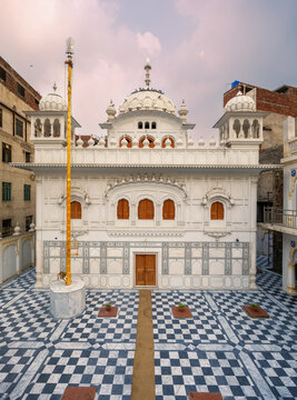 View of the white marble facade of Gurdwara Janam Asthan Guru Ram Das Ji with its distinctive domes and checkered marble courtyard in Lahore, Punjab, Pakistan.