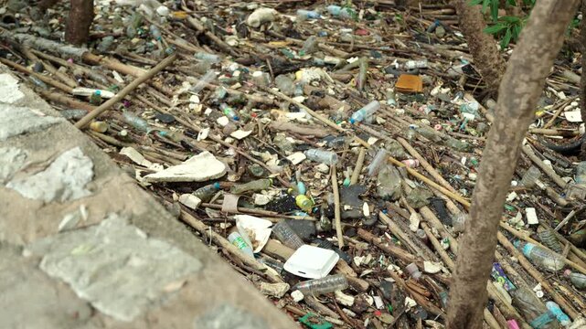 Plastic waste piled up in a forest. Highlighting the global waste crisis and environmental pollution. Waste separation, recycling, plastic reduction, climate change and sustainable living concept.
