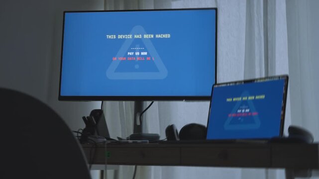 Computer in office or home showing warning message by hacker for ransom payment. Night in company or personal work station desk - laptop and monitor display request for money to release private data