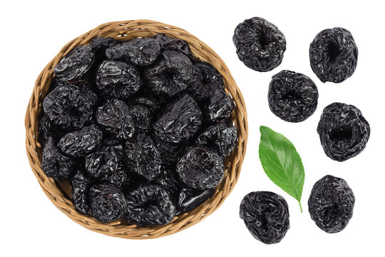 Prunes in wicker basket isolated on white background, heap of dried plums. Top view. Flat lay