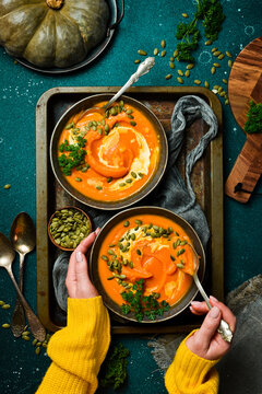 Two bowls of pumpkin porridge or cream soup with pumpkin seeds and cream. Autumn food concept. Top view.