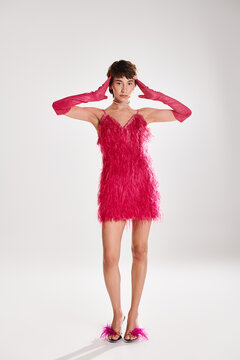 Stylish young woman showcases glamour in a vibrant pink feather dress