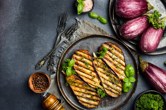 A plate of grilled eggplant. Grilled vegetables. Top view. On a gray concrete background.