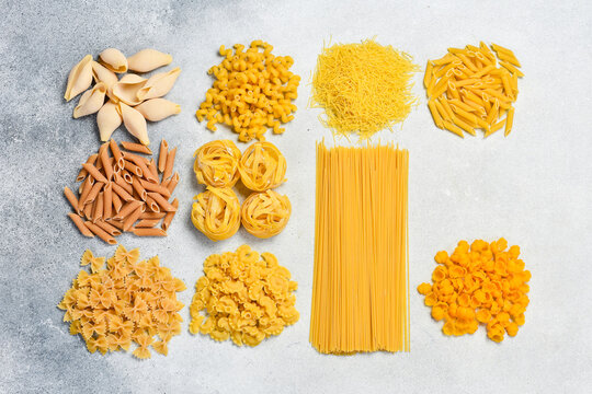 Pasta background. Different types of raw Italian pasta on light background. Top view.