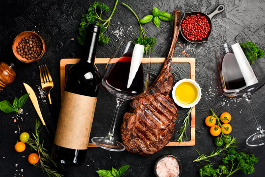 Bottled wine, glasses and Beef Tomahawk steak. Prime Black Angus beef steak and aged wine. Top view.