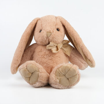 Professional studio product shot of a soft beige stuffed rabbit with long floppy ears. Adorable plush hare toy with a fabric bow for baby nursery decor and online store catalog.