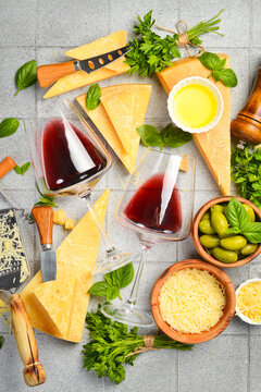 Cheese and wine. Assortment of hard Parmesan cheese, olives, basil and wine in glasses. Top view. Italian food concept.