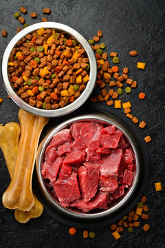 Raw beef meal in bowl, fresh, natural food for dog or cat. On a black stone background.