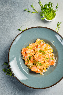 Italian pasta with shrimp and parmesan cheese. In a plate. Restaurant dish. Close up.