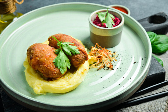 Two juicy meat patties with mashed potatoes and beetroot sauce. Close up. on a plate On a black stone background.