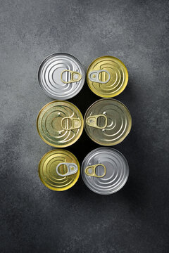 Vertical photo. Canned food in metal cans: fish, vegetables and fruits.