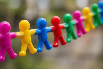 Obraz premium A line of colorful plastic figures are strung up against a blurred outdoor background.