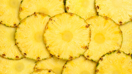 Naklejka premium Pineapple background. Yellow juicy slices of ripe pineapple. Close-up, macro photo.