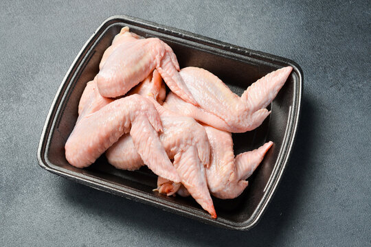 Fresh meat. Set of raw chicken wings. Meat on a plastic black container from the market. Close-up.