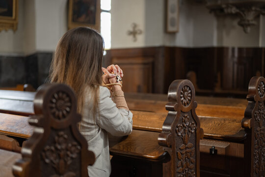 A woman prays inside a European Catholic church during Holy Mass, showing devotion and faith in a quiet moment of worship.