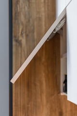 Lift-up cabinet door with metal hardware. Kitchen furniture construction detail.