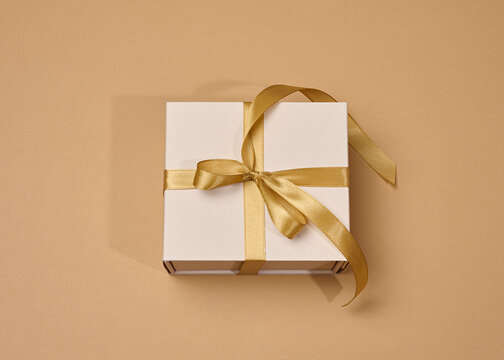 The box is tied with a golden ribbon on a beige background