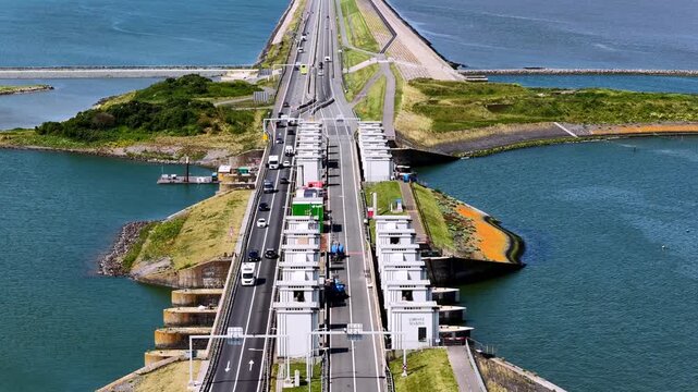 Aerial view of the Afsluitdijk causeway with traffic and road works on the highway and sluice gates surrounded by water in Kornwerderzand, Friesland, Netherlands.
