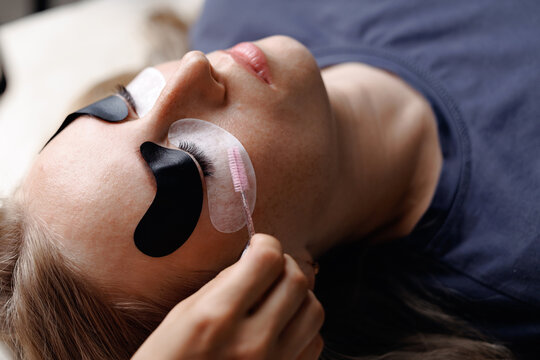 Eyelash extension procedure, top view. Master tweezers fake long lashes beautiful female eyes
